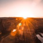 Captivating sunrise over Horseshoe Bend with sun rays illuminating the desert landscape.