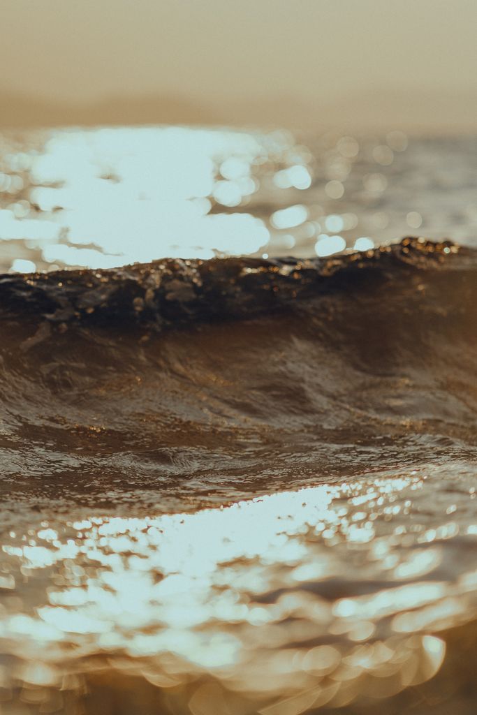Warm glowing ocean wave capturing the golden light of sunset creating a serene and contemplative mood.